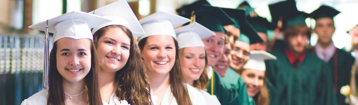 Flera high school studenter iklädda vita och gröna examenskläder.