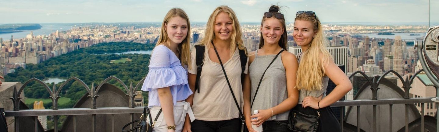 High school studenter poserar med vacker stadsvy i bakgrunden