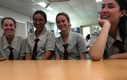 En utbytesstudent sitter med andra studenter vid ett bord i ett klassrum någonstans i Australien