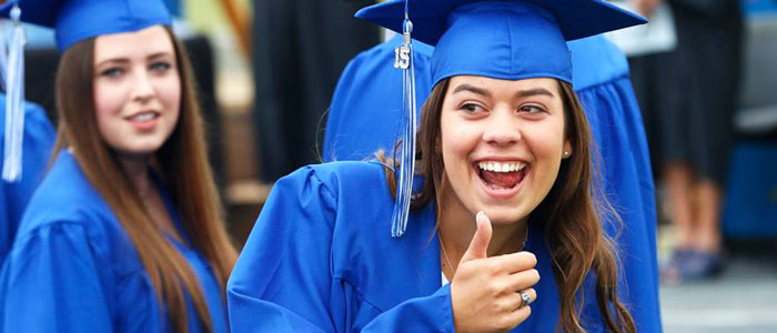 En student gör tummen upp på sin examensdag på Select high school i USA