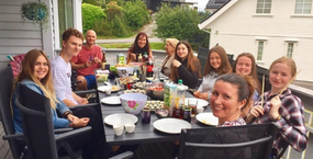 Studenter och värdfamiljen äter middag tillsammans utomhus