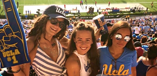 Tre studenter tittar på en match på en sportarena