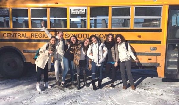 Kvinnliga high school studenter framför en gul amerikansk skolbuss